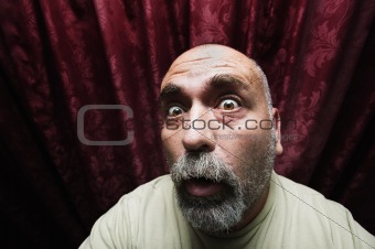 Worried man in front of red curtains