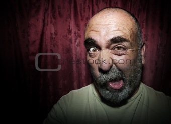 Man making a funny face in front of red curtains
