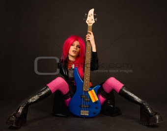 Attractive rock girl sitting with bass guitar