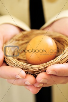Hands holding nest with egg