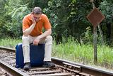 Man sitting on suitcase on a railway