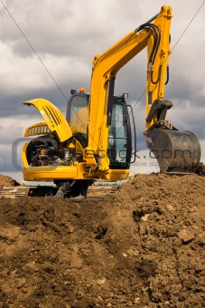 Excavator standing on soil with open engine