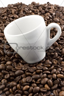 Classic white espresso cup on coffee beans