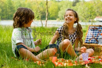 Two kids smiling while picknicking