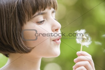 girl blowing a dandelion