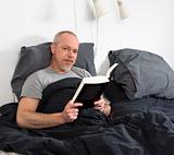 Confident man reading in bed