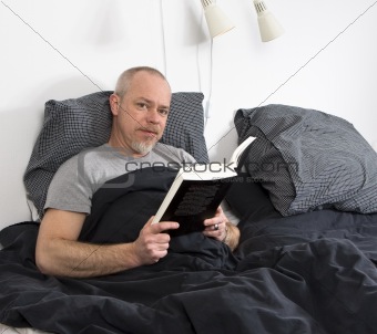 Confident man reading in bed