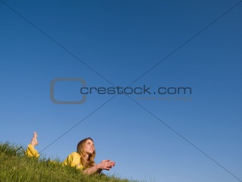 Happy girl lying on grass, looking dreamily towards blue sky