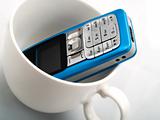 A mobile phone in a white cup