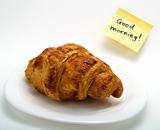 Croissant in white plate and yellow note