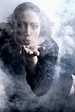 Woman with long curly hair blowing smoke