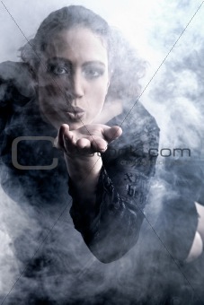 Woman with long curly hair blowing smoke