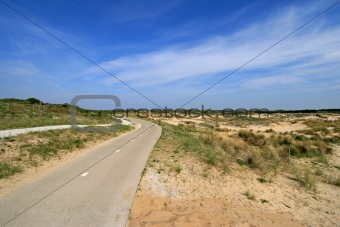 Dunes with empty road and blue sky