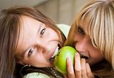 Two girls want to eat an apple