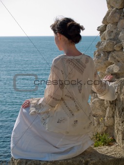 Lonely Young Woman on Stone Looking to Sea