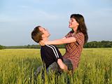 Young man Holding Wife in Field Smiling