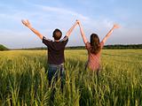 Young Couple in Field Holding Hands Up