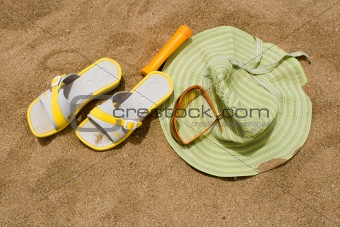 Woman hat, flip flops, sun glasses, sun block on sand
