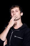 The young man smokes a cigarette. Isolated on a black background