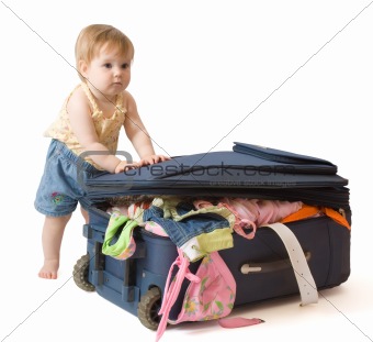Baby standing near the suitcase