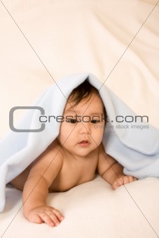 ethnic baby boy lying down under blanket (peekaboo)