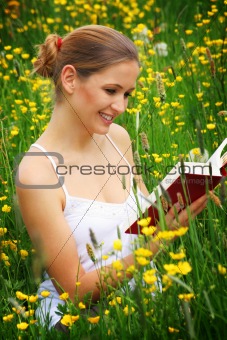 happy woman on a meadow with a book
