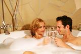 a couple is taking a bath with champagne in a glass