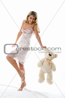 The young charming girl plays with a bear