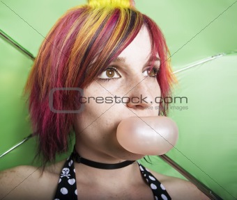 Pretty Woman with a Green Umbrella Blowing a Bubble