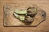 Two artichokes on wooden table.