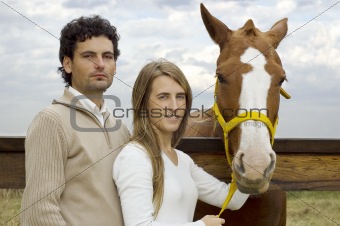 Young couple standing by their horse