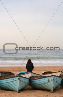 lonely person with boats, beach and sea  in sunset light