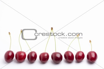 row of red cherries on white background