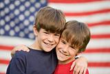 Brothers Hugging in Front of Flag