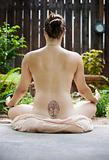 Back of a nude woman meditating